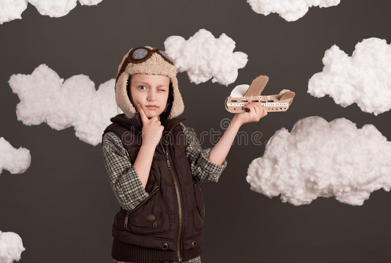 Une fille joue avec un avion en carton et des rêves de devenir un pilote vêtu d'une chemise rétro et casque de style avec des lune image libre de droits
