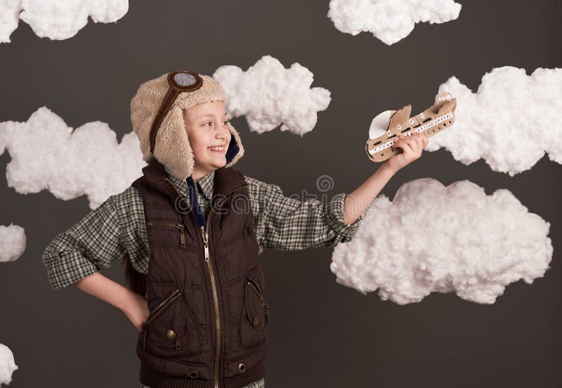 Une fille joue avec un avion en carton et des rêves de devenir un pilote vêtu d'une chemise rétro et casque de style avec des lune photos libres de droits