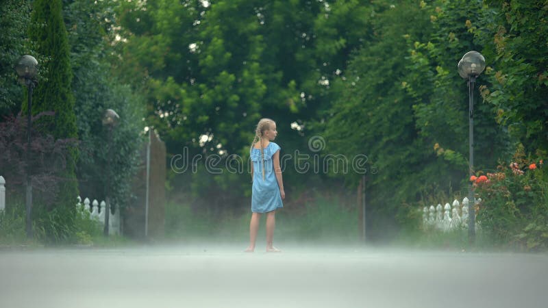 Une fille joyeuse agitant la main, debout pieds nus dans le brouillard, atmosphère mystérieuse banque de vidéos