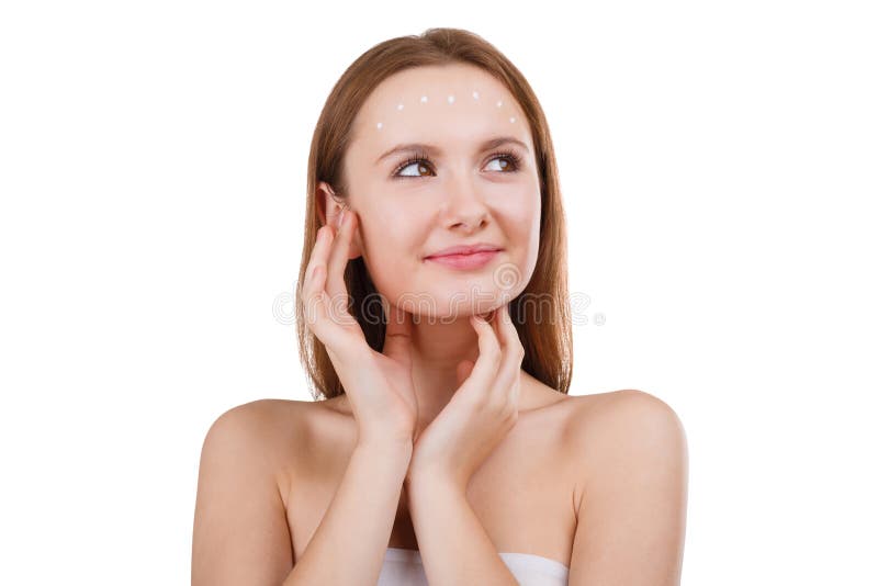 Une fille mignonne applique une crème cosmétique sur le visage et recherche avec un sourire Le concept de la beauté D'isolement photographie stock libre de droits Une fille mignonne applique une crème cosmétique sur le visage et recherche avec un sourire Le concept de la beauté D'isolement photographie stock libre de droits