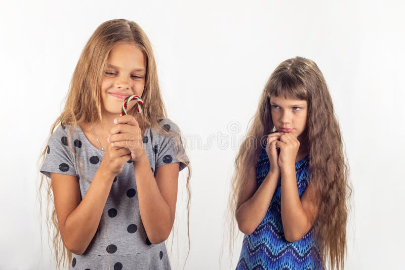 Une fille prend une lucette dans des ses mains, l'autre derrière ses regards à la fille avec reproches photo libre de droits Une fille prend une lucette dans des ses mains, l'autre derrière ses regards à la fille avec reproches photo libre de droits