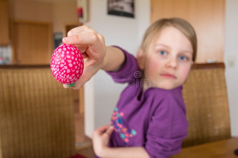 Une fille 7 an sourit et tient un oeuf de pâques dans la caméra, profondeur de champ images libres de droits Une fille 7 an sourit et tient un oeuf de pâques dans la caméra, profondeur de champ images libres de droits