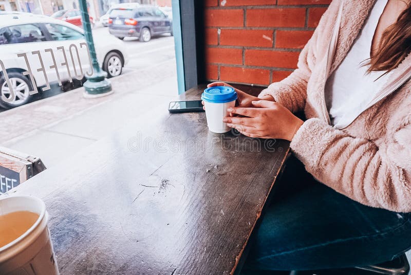 Une fille tenant une tasse de café avec un couvercle bleu photos stock Une fille tenant une tasse de café avec un couvercle bleu photos stock