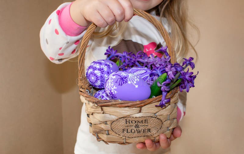 Une fille tenant un panier avec les oeufs et les fleurs peints en fleurs lilas, pour Pâques photos stock Une fille tenant un panier avec les oeufs et les fleurs peints en fleurs lilas, pour Pâques photos stock
