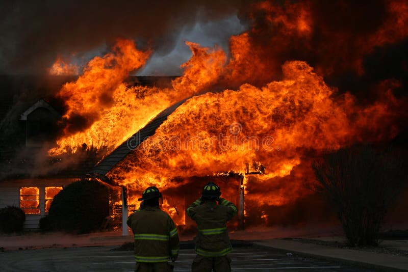 Fireman look on as a two story building goes up in smoke, seeing to it that the burn is controlled and not allowed to spread beyond the immediate vivacity. Fireman look on as a two story building goes up in smoke, seeing to it that the burn is controlled and not allowed to spread beyond the immediate vivacity.