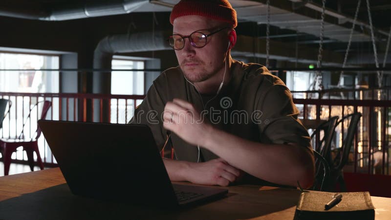 Une freelance réfléchie dans une pièce sombre avec un ordinateur portable.