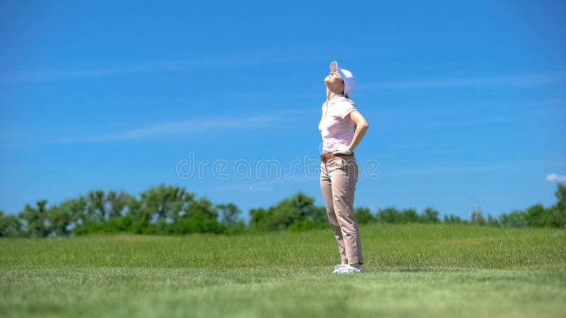 Inexperienced woman golfer dissatisfied about failed shot, looking up, loser, stock photo. Inexperienced woman golfer dissatisfied about failed shot, looking up, loser, stock photo