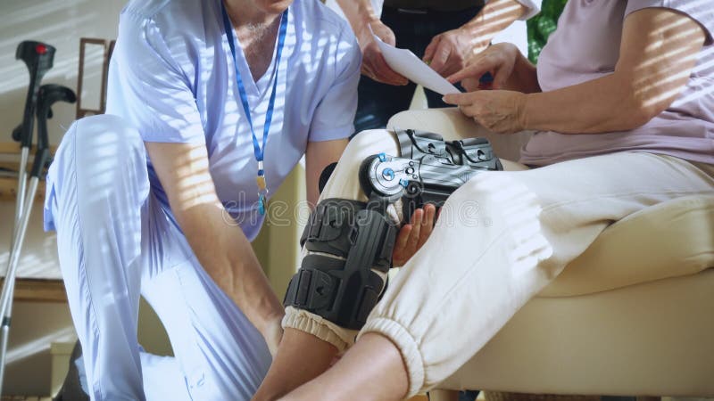 Une infirmière aide à mettre une servitude sur la jambe d'une patiente âgée banque de vidéos