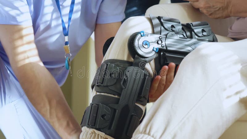 Une infirmière aide à mettre une servitude sur la jambe d'une patiente âgée banque de vidéos