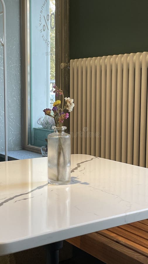 Une installation minimaliste de table avec de belles fleurs en plus d'un radiateur confortable pour l'ambiance. Une élégante scène intérieure agrémentée d'une table simple ornée de fleurs et d'un accent radiateur cosy