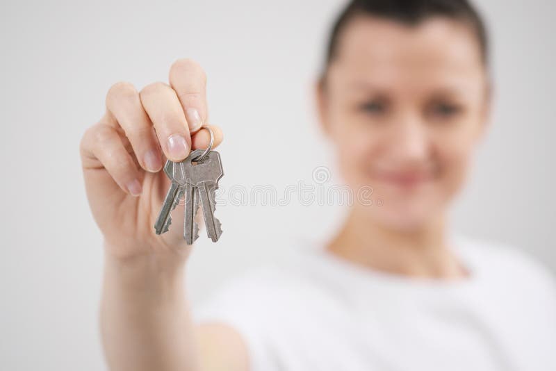Une jeune belle fille de brune dans un T-shirt blanc tient dans des ses mains les clés sur une nouvelle maison, dans la perspecti photo libre de droits Une jeune belle fille de brune dans un T-shirt blanc tient dans des ses mains les clés sur une nouvelle maison, dans la perspecti photo libre de droits