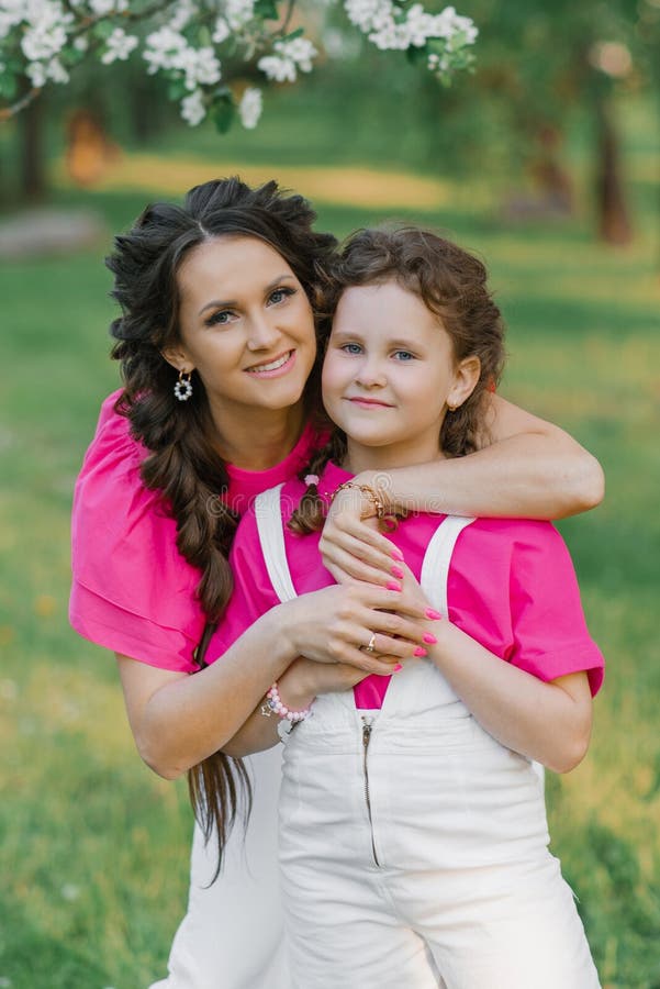 Une jeune belle maman est heureuse et embrasse sa fille qui sourit.