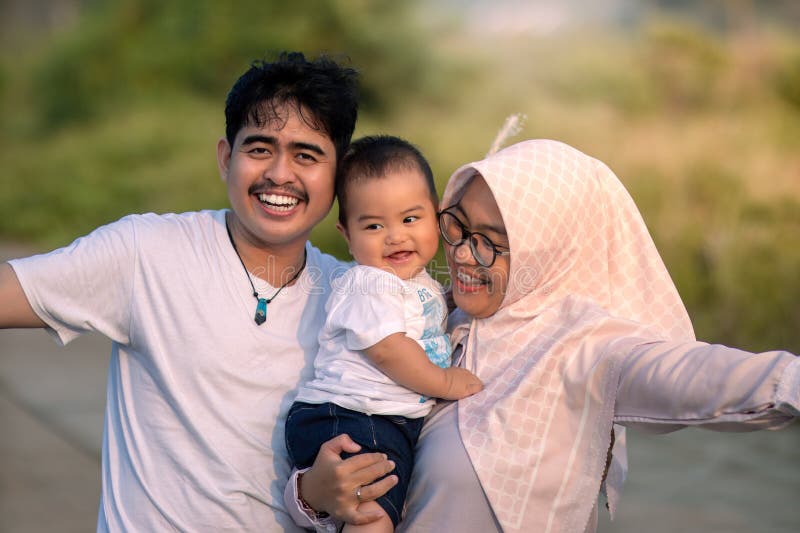Une jeune famille qui a l'air heureuse et riant haut avec le père mère et le petit garçon. mère tenant le bébé. ambiance photo photo libre de droits