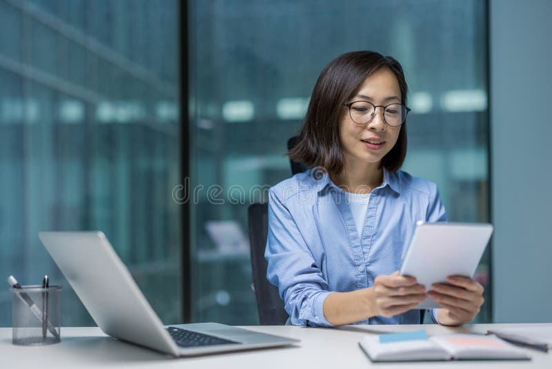 Une jeune femme asiatique professionnelle travaille à son bureau en utilisant une tablette dans un bureau moderne. images libres de droits