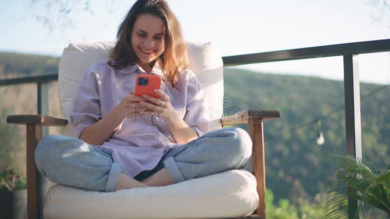 Une jeune femme caucasienne utilise un smartphone assis sur une terrasse clips vidéos