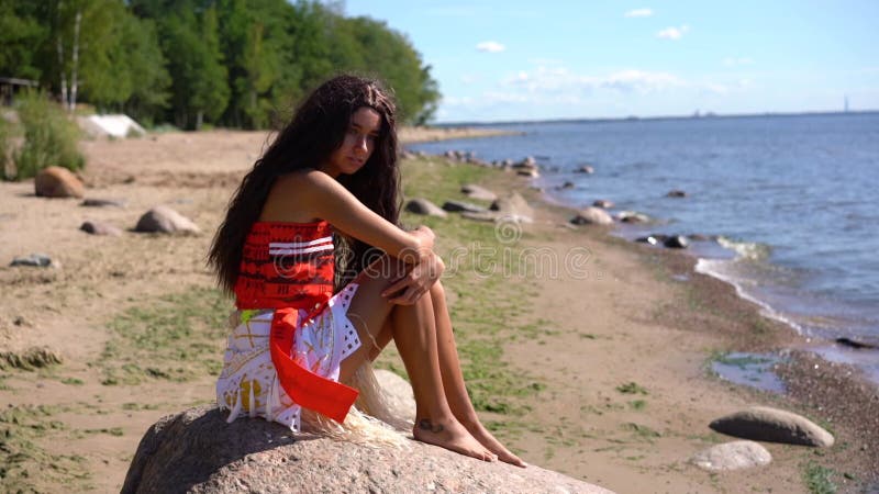 Une jeune femme est assise sur une pierre au bord de la baie par une journée ensoleillée clips vidéos