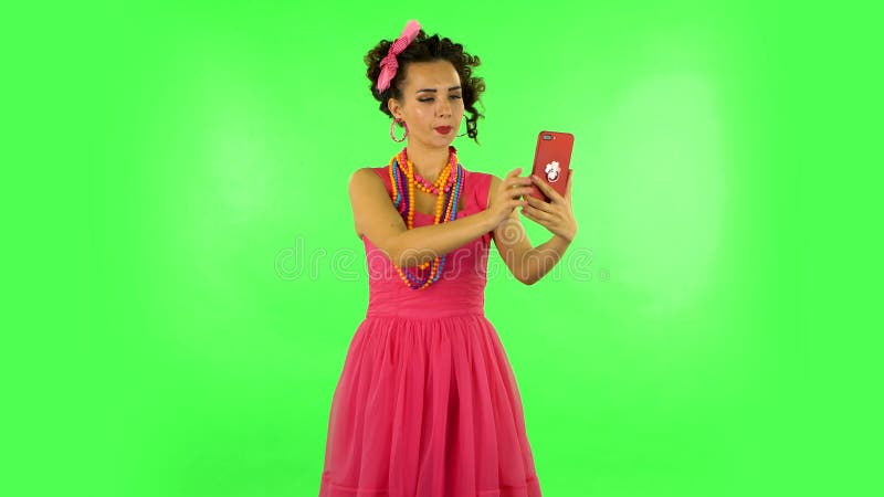 Une jeune femme fait le selfie sur son téléphone portable puis regarde des photos sur écran vert banque de vidéos
