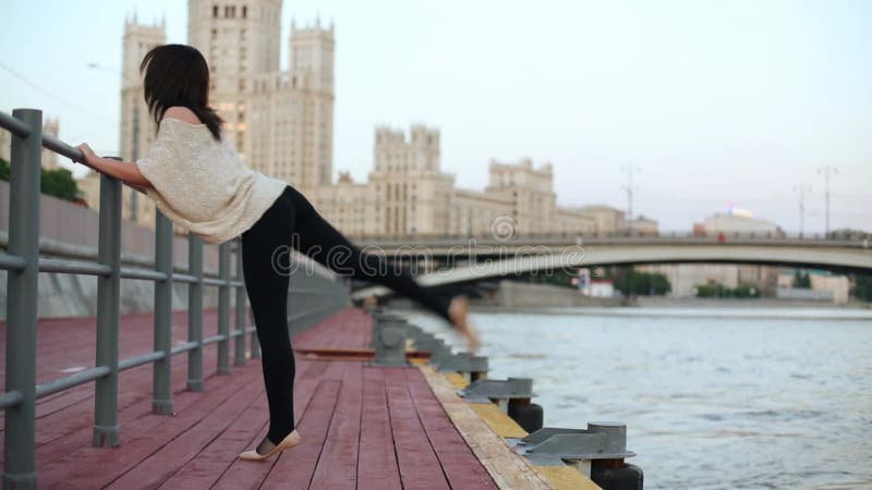 Une jeune femme fait un exercice extensif près du banque de vidéos