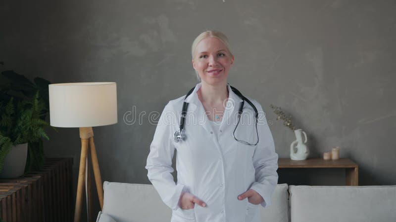 Une jeune femme médecin sourit et regarde la caméra en blanc