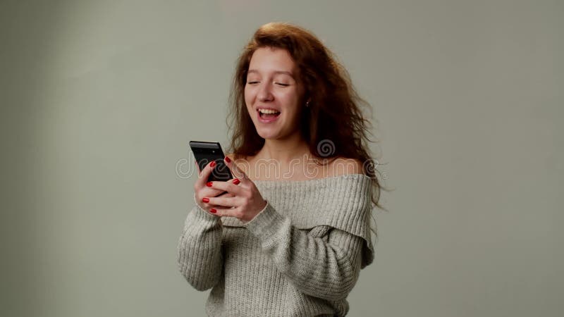 Une jeune femme positive utilise un smartphone et heureuse dans les émotions flurées gagnant une grande somme d'argent un casino e