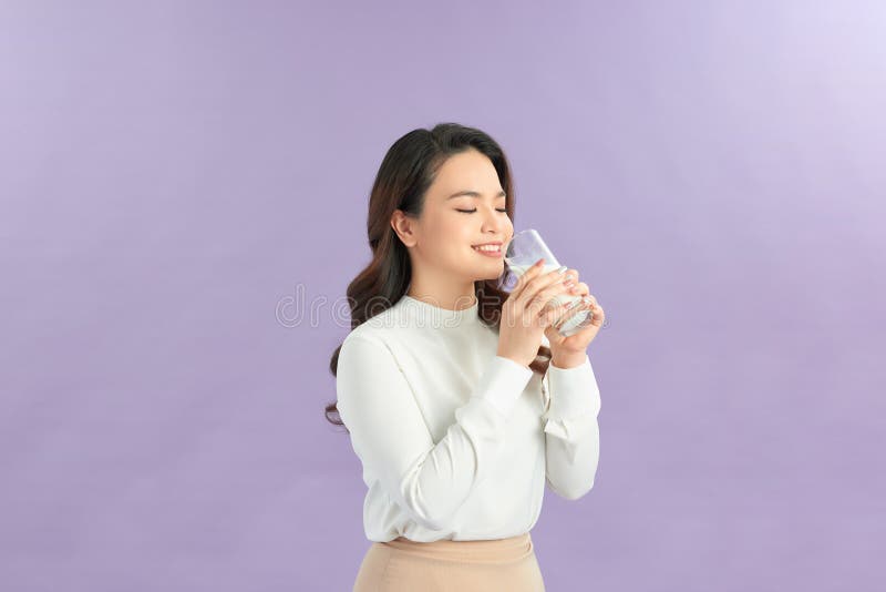 Une jeune femme riant avec un verre de lait. Jeune sourire joyeuse femme porter des vêtements blancs tenir à la main verre