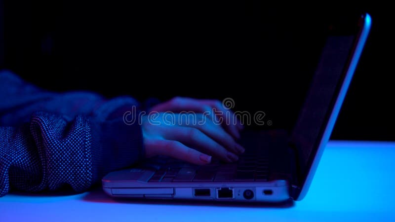 A young woman is typing on a laptop keyboard. Hands close up. Hacker makes a hack through a laptop. Blue and red light falls on hands. 4k. A young woman is typing on a laptop keyboard. Hands close up. Hacker makes a hack through a laptop. Blue and red light falls on hands. 4k