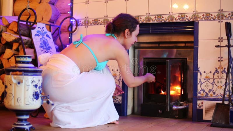 Une jeune femme tire le feu dans la cheminée au bain banque de vidéos