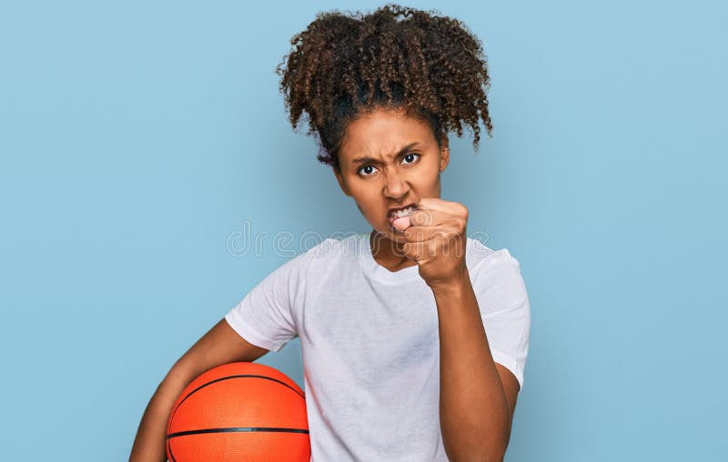Une jeune fille africaine américaine jouant au baseball tenant des battes et du ballon agacé et frustré criant de colère fou avec images stock