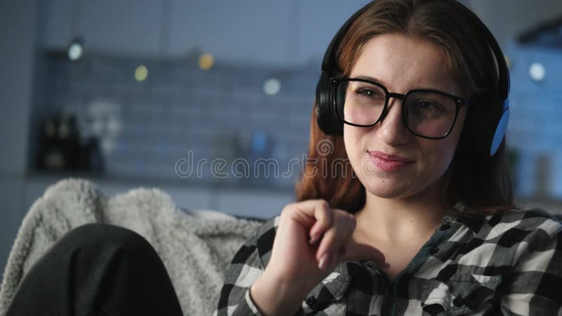 Une jeune fille attrayante écoute de la musique et chante dans une salle du soir banque de vidéos