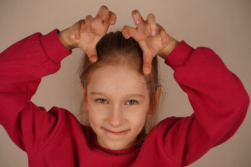 Une jeune fille joyeuse sourit avec joie en formant ses mains avec des griffes comme des animaux. Son geste imaginatif dégage de l photos stock
