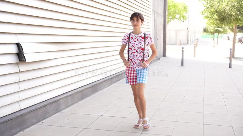 Une jeune fille joyeusement marcher sur une journée brillante et ensoleillée habillée en style de mode décontracté banque de vidéos