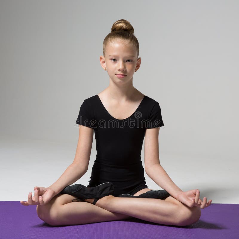 Une jeune fille s'assied dans une pose de lotus méditation Enfant photo stock Une jeune fille s'assied dans une pose de lotus méditation Enfant photo stock