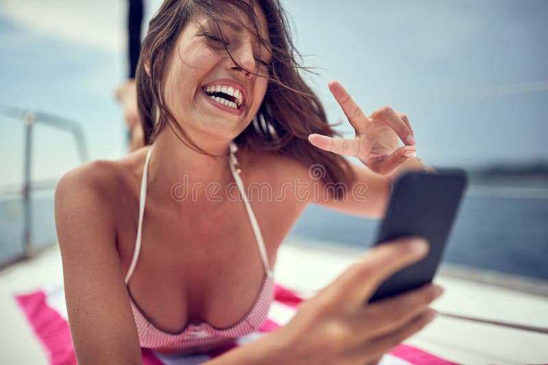 Une jeune fille sexy discute en vidéo sur un smartphone tout en profitant d'un bain de soleil. vacances d'été photo stock