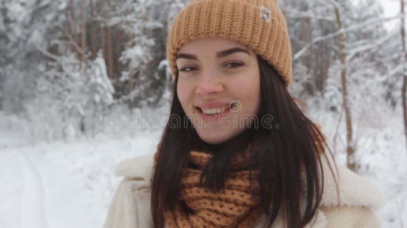 Une jeune fille tient une boîte-cadeau dans ses mains et sourit joyeusement debout dans la forêt d'hiver adjacente banque de vidéos