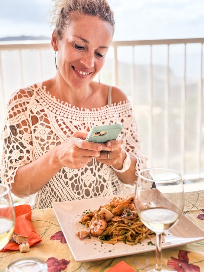 Une jolie femme adulte prenant en photo sa nourriture avant de déjeuner. spaghetti aux pâtes avec poisson. photo de femmes moderne images libres de droits