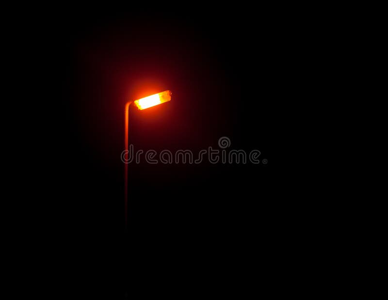 Une lumière rougeoyante lumineuse de réverbère dans l'extérieur sombre la nuit photos stock Une lumière rougeoyante lumineuse de réverbère dans l'extérieur sombre la nuit photos stock