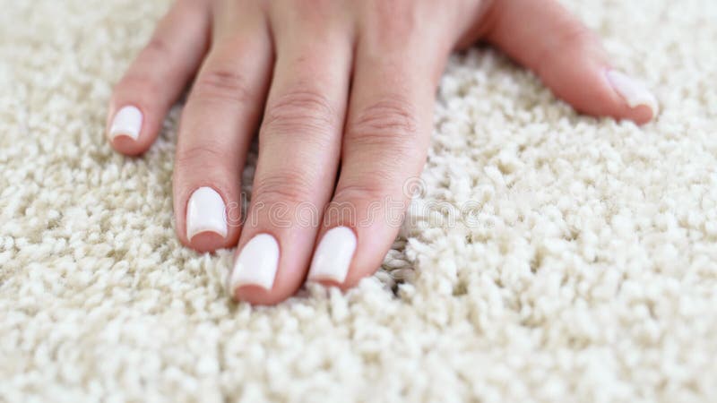 Une main femme touchant le beige moquette intérieure en polypropylène. banque de vidéos