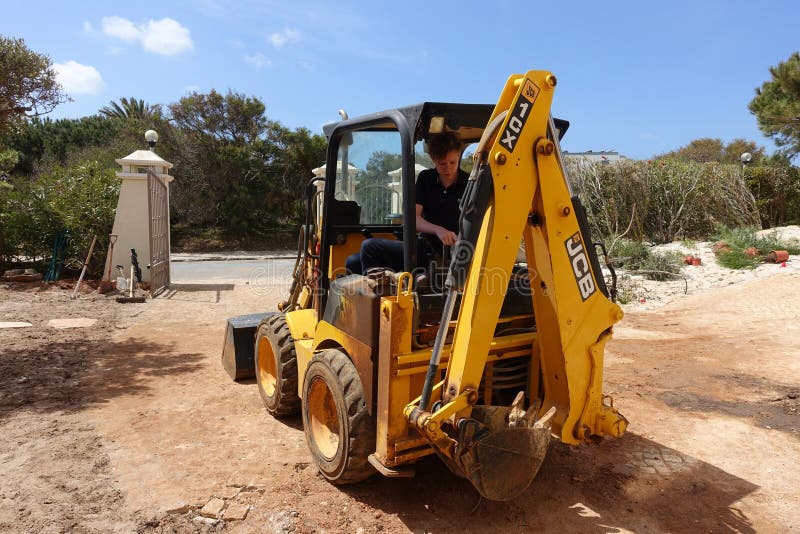 Une mini-digeuse JCB utilisée pour effectuer des travaux d'aménagement paysager dans un jardin d'avant image libre de droits Une mini-digeuse JCB utilisée pour effectuer des travaux d'aménagement paysager dans un jardin d'avant image libre de droits