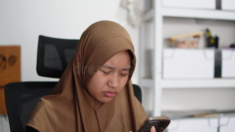 Une musulmane asiatique semble perplexe lorsqu'elle lit un message sur un smartphone clips vidéos