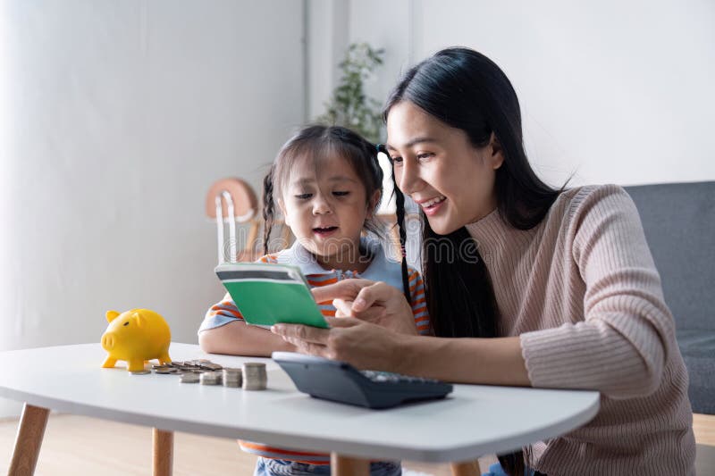 Une mère et une fille diversifiées apprenant à économiser de l'argent avec calculatrice de banque de piges jaune et ordinateur por photographie stock