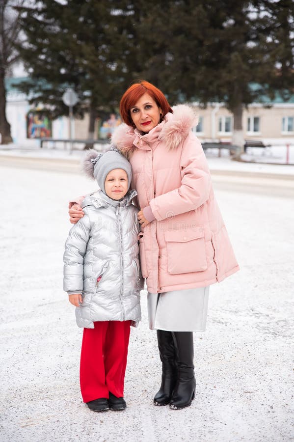 Une mère et une fille russes souriant ensemble dehors vêtue de manteaux assortis. la fille se tient à côté de sa mère images stock