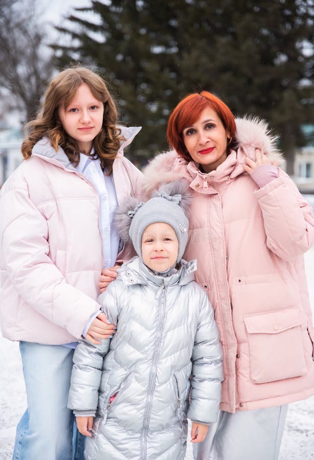 Une mère et ses deux filles un adolescent et un enfant plus jeune profitent ensemble d'une journée d'hiver enneigée. ils partagent le rire et la chaleur au milieu du froid entouré d'un magnifique paysage gelé