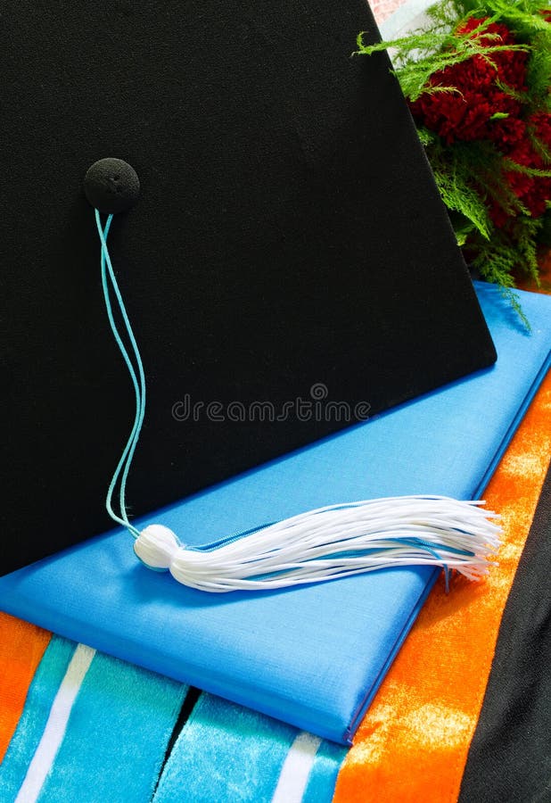 Une obtention du diplôme a placé avec le bouquet, le chapeau, le gland, la robe, le capot et le diplôme images stock Une obtention du diplôme a placé avec le bouquet, le chapeau, le gland, la robe, le capot et le diplôme images stock