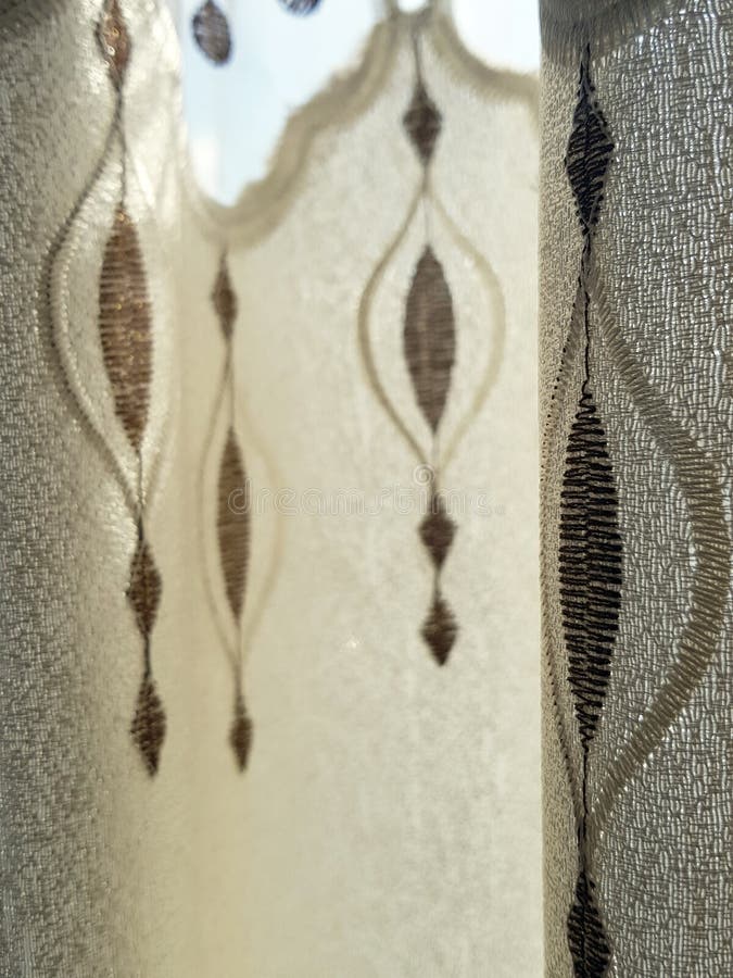 Part of beautifully draped curtain on the window in the room. Floral tieback. Close up of piled curtain. Beige and brown luxury curtain home interior decor. Part of beautifully draped curtain on the window in the room. Floral tieback. Close up of piled curtain. Beige and brown luxury curtain home interior decor