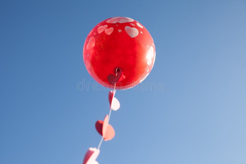 Une petite fille avec le ballon rouge sur le ciel bleu photo stock Une petite fille avec le ballon rouge sur le ciel bleu photo stock