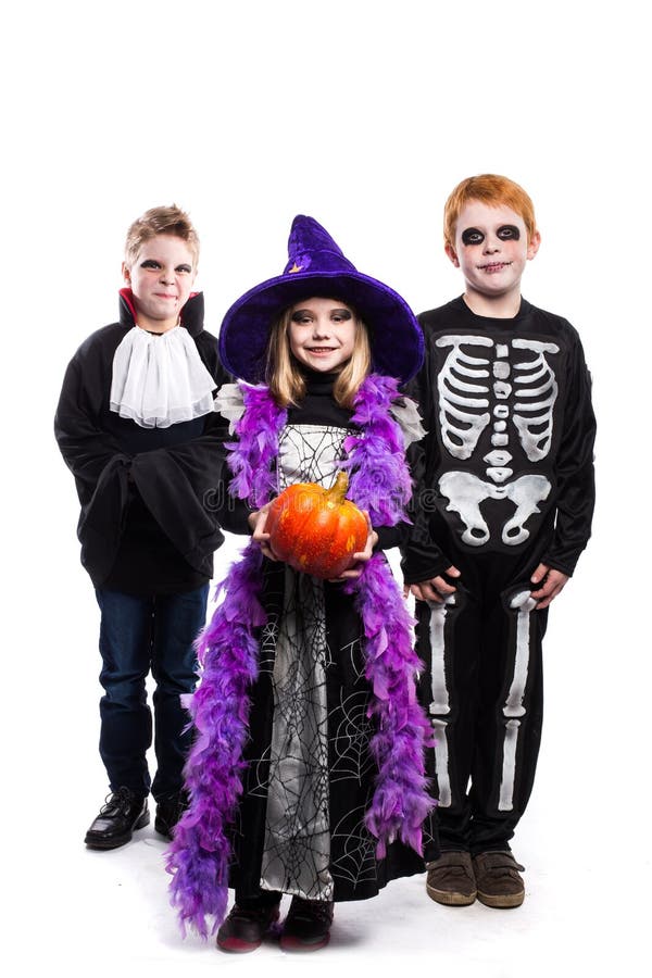 Une petite fille et deux garçons ont habillé les costumes de Halloween : sorcière, squelette, vampire images stock Une petite fille et deux garçons ont habillé les costumes de Halloween : sorcière, squelette, vampire images stock