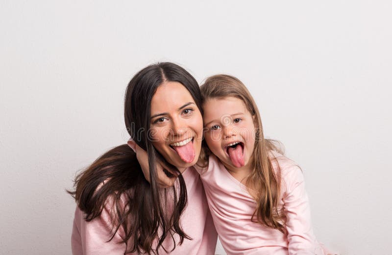 Une petite fille et sa mère collant des langues dans un studio image libre de droits Une petite fille et sa mère collant des langues dans un studio image libre de droits