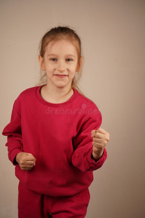 Une petite fille rousse se tient les poings serrés, émanant d'une détermination féroce. Son regard intense la révèle image stock