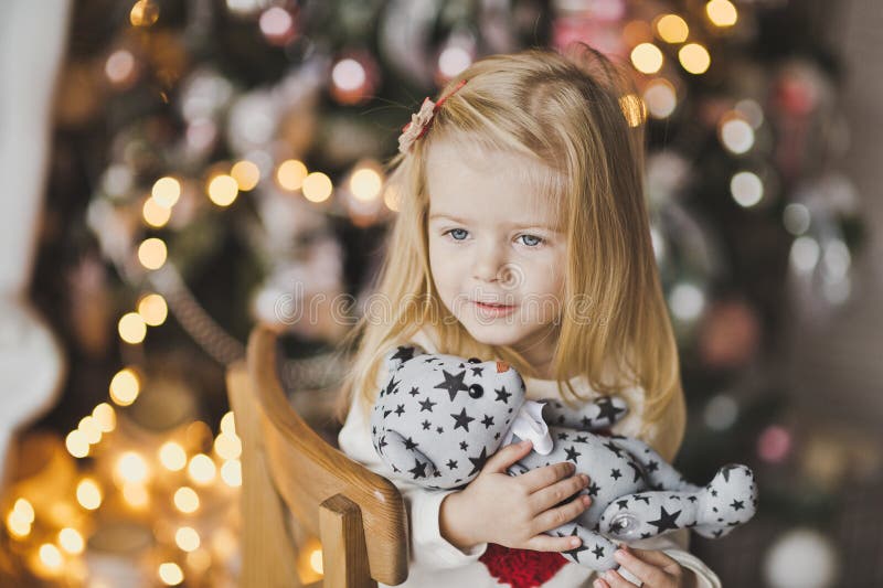 Une petite fille s'asseyant près de l'arbre de Noël dans l'attente d'un MI images stock