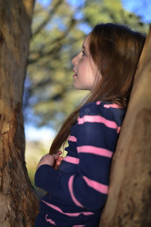 Une petite fille se reposant sur une branche d'arbre photo stock Une petite fille se reposant sur une branche d'arbre photo stock